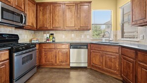 A kitchen with wooden cabinets, a stainless steel stove, and a dishwasher.