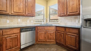 A kitchen with wooden cabinets, a stainless steel dishwasher, and a refrigerator.