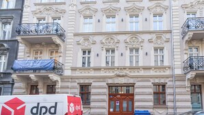 A building with ornate architectural details, a blue banner with contact information, and a delivery van parked in front. - Chopina Glamour Apartment (Katowice)