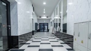 A hallway with a checkered floor, marble walls, and lockers on the right. - Chopina Glamour Apartment (Katowice)