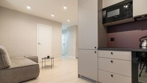 A modern kitchen with a microwave, oven, and a small dining table. - Chopina Glamour Apartment (Katowice)