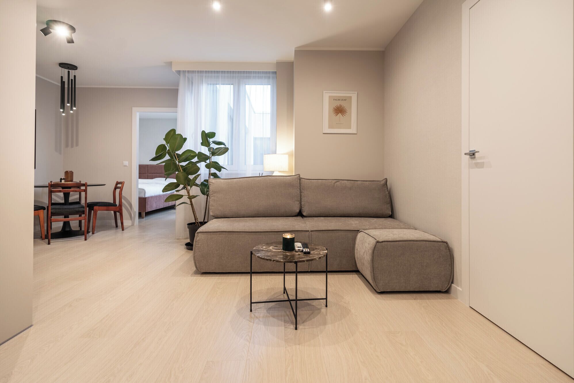 Un salon moderne avec un canapé, une petite table ronde et un coin repas avec des chaises.