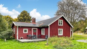 A red wooden house with a porch and outdoor seating. - 2 bedroom stunning home in öxnevalla (Öxnevalla)