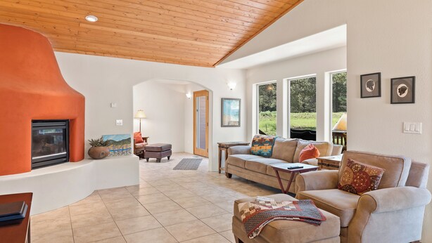 A spacious living room with a fireplace, comfortable seating, and large windows offering a view of the outdoors. - Convenient Location | Fireplace | Pet Friendly | Country Club Villas 13 (Angel Fire)