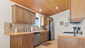 A kitchen with wooden cabinets, a stainless steel refrigerator, a dishwasher, and a coffee maker. - Convenient Location | Fireplace | Pet Friendly | Country Club Villas 13 (Angel Fire)