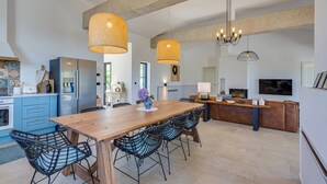 A modern kitchen with a wooden dining table, black wireframe chairs, and a central island with a sink and countertop. - Villa Terossa (Kvarner - Skrbčići) (Skrbčići)