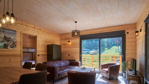 A wooden interior with a sofa, chairs, a table, and a TV. - Chalet du Souillet with Mountain Views, Private Terrace and Wi-Fi (Saint-Pierre-d'Entremont)
