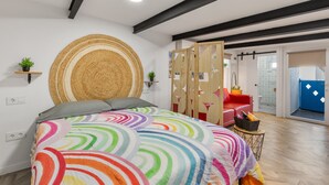 Ein Schlafzimmer mit einem Bett, einem runden, gewobenen Kopfteil, einem roten Sessel und einer Holzwand.
