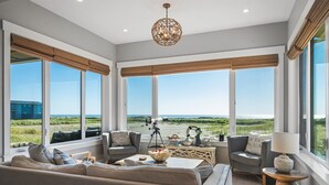 Amplia sala de estar con ventanas grandes, un sofá confortable, una mesa de centro y un telescopio.