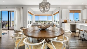 Una cocina moderna con armarios blancos, una mesa de comedor de madera y una lámpara de araña.