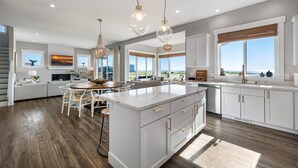 Una cocina moderna con una isla grande, armarios blancos e iluminación colgante.