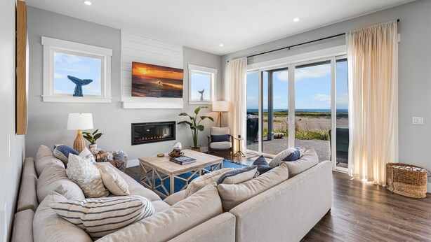 Una sala de estar moderna con un sofá grande, una chimenea y vistas a la playa.