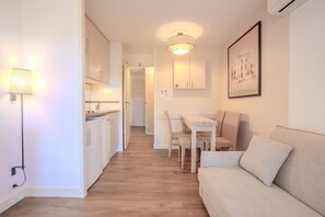 Una cocina moderna con armarios blancos, una mesa de comedor con sillas y un sofá de color neutro.