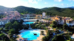 Un resort con varias piscinas, un patio central y montañas al fondo.