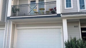 Een twee verdiepingen tellend huis met een balkon, een garage en een kleine voortuin.