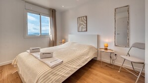A hotel room with a large bed, a bedside table with a lamp, a chair, a mirror, and a window with a view. - Villa 'Costacabana -  La Luna' with Sea View, Private Pool and Wi-Fi (Lloret de Mar)