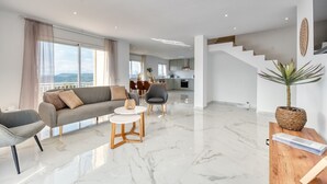 A modern living room with a sofa, chairs, a coffee table, and a staircase leading to an upper level. - Villa 'Costacabana -  La Luna' with Sea View, Private Pool and Wi-Fi (Lloret de Mar)