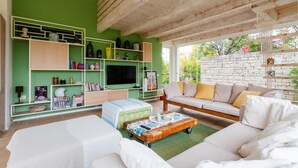A modern living room with a green accent wall, wooden ceiling, and a stone wall.