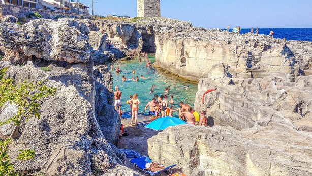 A rocky coastal area with a clear swimming pool surrounded by cliffs.