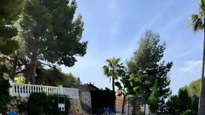 Una piscina con sillas de descanso, un muro de piedra y un edificio pequeño.
