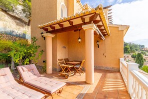 A terrace with lounge chairs, a table, and a pergola.