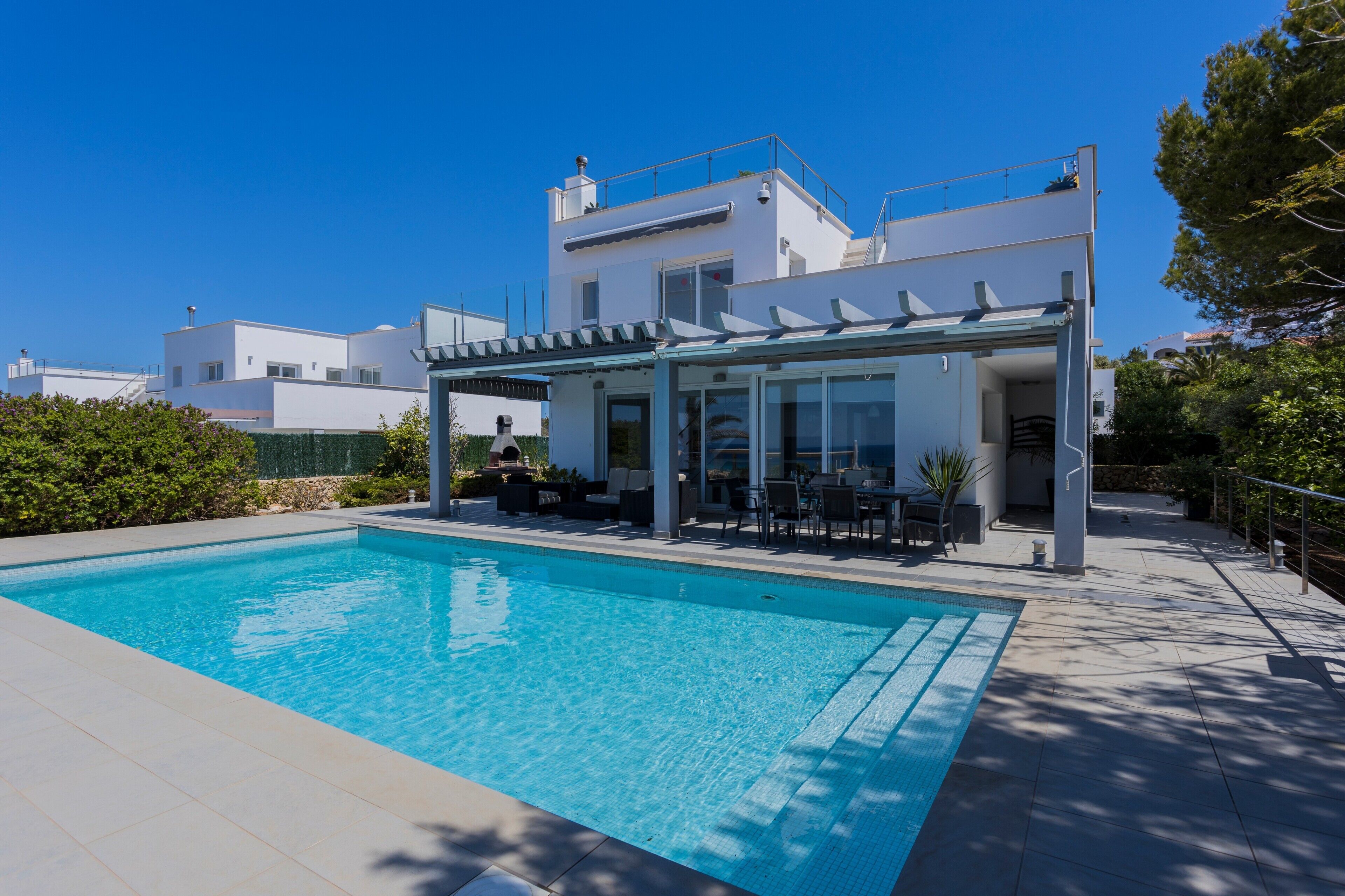 A modern house with a swimming pool, outdoor seating, and a covered patio.