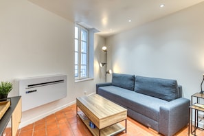 Un salon moderne avec un canapé, une table basse en bois, un lampadaire et une fenêtre équipée de stores.