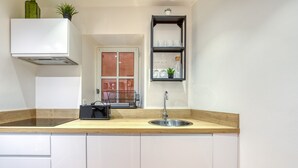 A kitchen with a wooden countertop, white cabinets, a stainless steel sink, a black coffee machine, a window with a view, and a shelf with glassware and a plant. - Holiday Home 'La Reine' with Wi-Fi and Air Conditioning (Béziers)