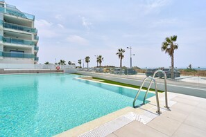 A swimming pool with clear water, a building with balconies, and palm trees. - Apartment 'Morning Sun Duna 1' with Sea View, Wi-Fi and Air Conditioning (Torrox Costa)