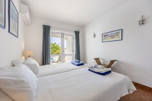 Une chambre d’hôtel avec deux lits, une vue sur l’extérieur, un tableau au mur et une petite table avec des serviettes.