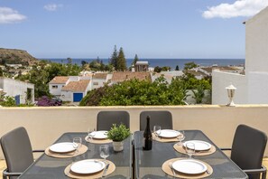 A table set for four with a view of the sea and buildings in the background.