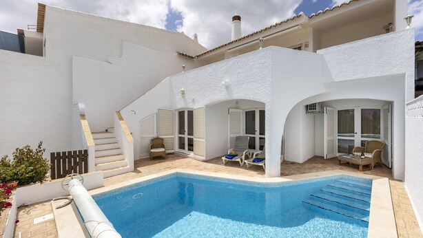 Eine moderne Villa mit Swimmingpool, Sitzgelegenheiten im Freien und einer Treppe zum Obergeschoss.