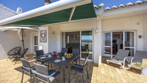 Une terrasse extérieure avec une table dressée pour les repas, des chaises et un espace abrité.