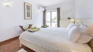 Ein Hotelzimmer mit einem Bett, einem Sessel, einem Tisch, einem Fenster und einer Wand-Klimaanlage.