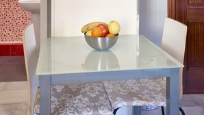 A dining table with a bowl of fruit, a chair, and a patterned tablecloth. - Casa Curro — Cozy Studio with Garden Views in Baena (Baena)