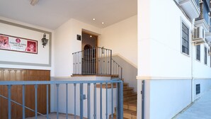A staircase with a blue metal railing, a wooden door, and a wall-mounted light fixture. - Casa Curro — Cozy Studio with Garden Views in Baena (Baena)