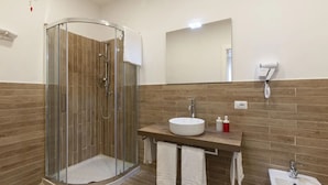 A modern bathroom with a glass-enclosed shower, a sink with a mirror, and a bidet.