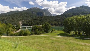 A mountainous landscape with a lake, trees, and a bridge.