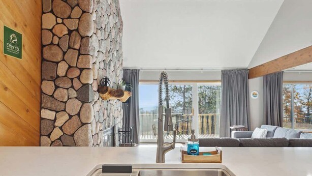 A modern kitchen with a stone wall, a sink, and a view of the outdoors. - Shanty Creek Retreat! (Bellaire)