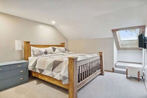 A bedroom with a bed, a dresser, a window, and a small table. - Shanty Creek Retreat! (Bellaire)
