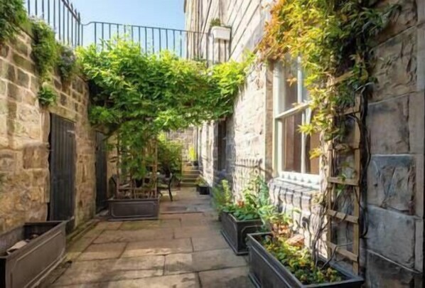 Stroll through a historic alleyway lined with stone buildings and lush greenery.