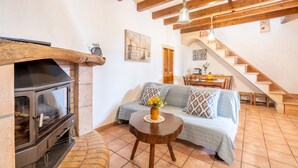 Ein gemütliches Wohnzimmer mit Kamin, einer Couch, einem Essbereich und einer Treppe.