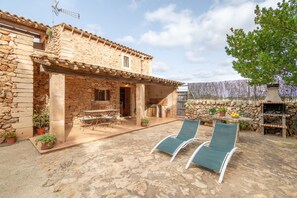 A stone house with a patio, outdoor furniture, and a barbecue area. - Country house very close to one of the most beautiful beaches of Mallorca (Illes Balears)