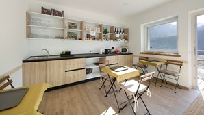 Una cocina moderna con armarios de madera, un comedor con mesa y sillas, y un amplio ventanal con vistas a la montaña.