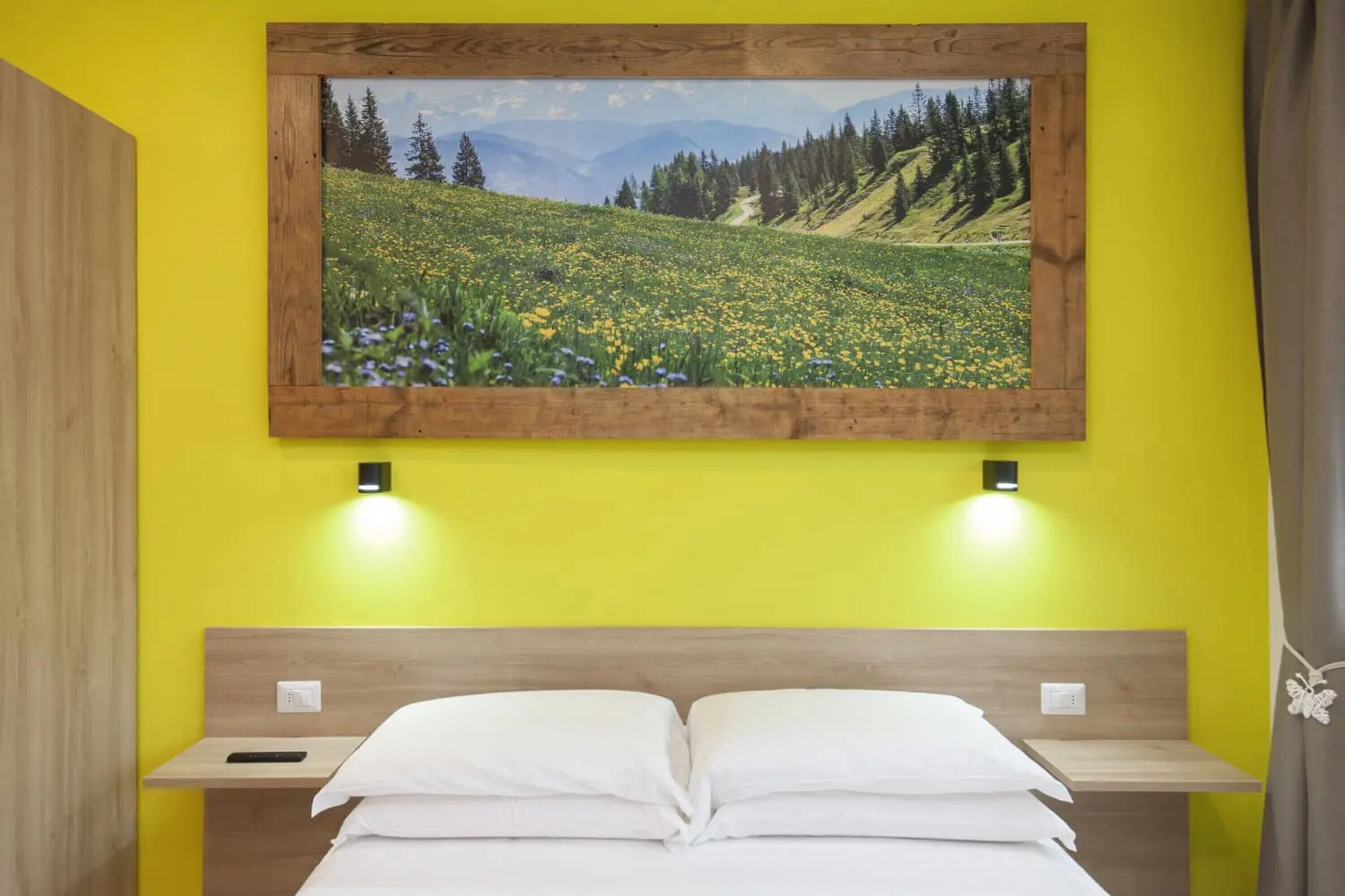 Ein Bett mit weißen Leinen, einem hölzernen Kopfteil und einem Nachttisch mit Fernbedienung.