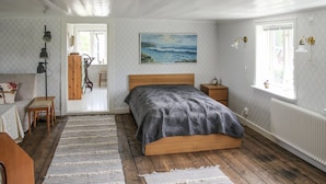 A bedroom with a wooden bed, a painting of a beach, a radiator, and a window with curtains. - Stunning home in älekulla with WiFi (Älekulla)