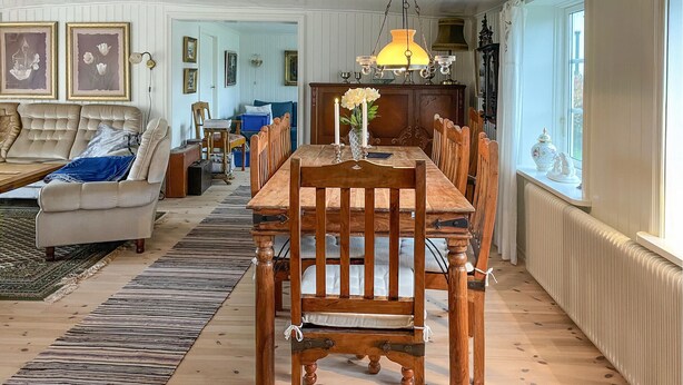 A dining area with a wooden table and chairs, a blue sofa, and a patterned rug. - Stunning home in älekulla with WiFi (Älekulla)