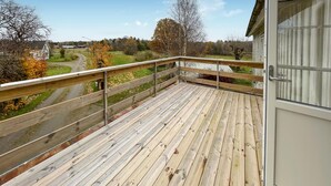 A wooden deck with a metal railing, overlooking a rural landscape with houses and trees. - Stunning home in älekulla with WiFi (Älekulla)