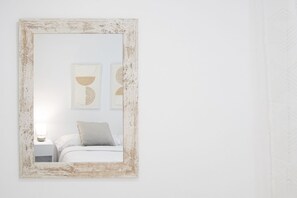A bedroom with a bed, a nightstand, and a wall-mounted mirror with a distressed frame.