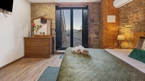 A bedroom with a bed, dresser, mirror, and a view through a door.